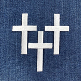 Three white cross patches on a blue denim background