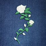 Embroidered white rose patch on a blue denim fabric
