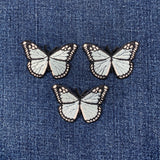 Three light blue butterfly patches on a denim background