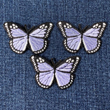 three light purple butterfly patches on a denim background