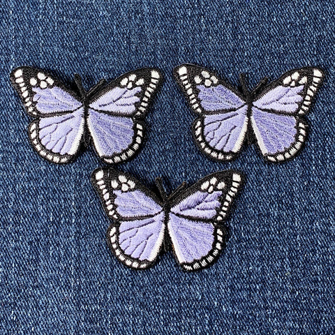 three light purple butterfly patches on a denim background