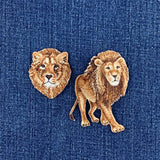 Two lion-themed patches, one lion head and one full lion, displayed on a blue denim fabric background.