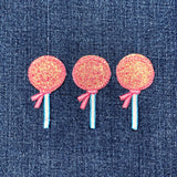 Three pink lollipop-shaped patches against a denim background