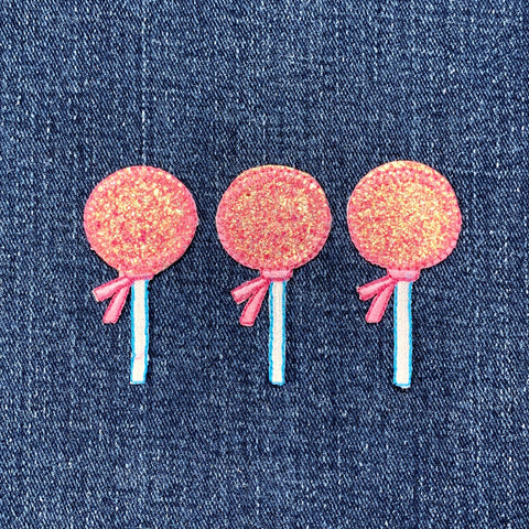 Three pink lollipop-shaped patches against a denim background