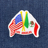 Embroidered patch with American and Mexican flags and 'Los Angeles' text on denim fabric.
