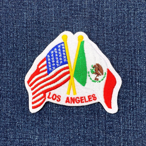 Embroidered patch with American and Mexican flags and 'Los Angeles' text on denim fabric.