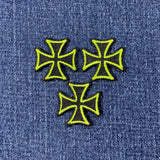 Three neon green and black cross patches on a denim background
