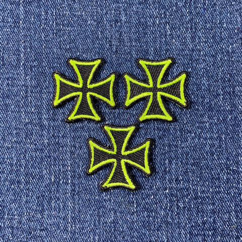 Three neon green and black cross patches on a denim background