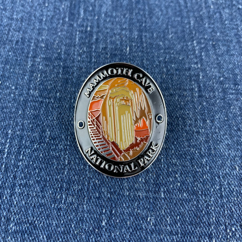 An oval medallion with a depiction of Mammoth Cave National Park, designed to be attached to a walking stick on a denim background