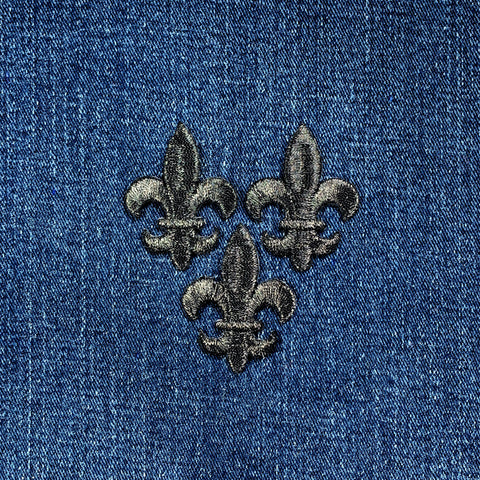 Three embroidered black fleur-de-lis patches on blue denim fabric