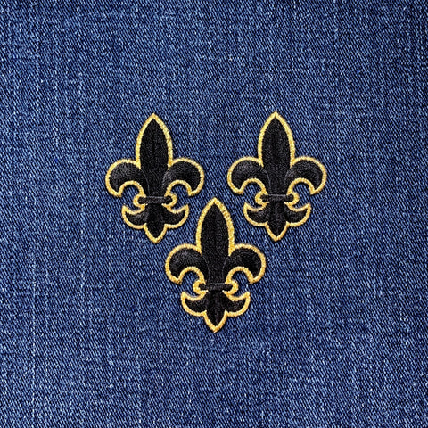 Three embroidered fleur-de-lis patches on a blue denim background