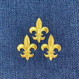 Three gold fleur-de-lis designs on a blue denim background
