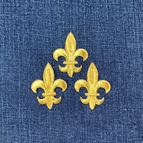 Three gold fleur-de-lis designs on a blue denim background