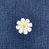 White flower-shaped patch with a yellow center on a denim background