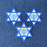 Three Star of David patches with Menorah design on a denim background