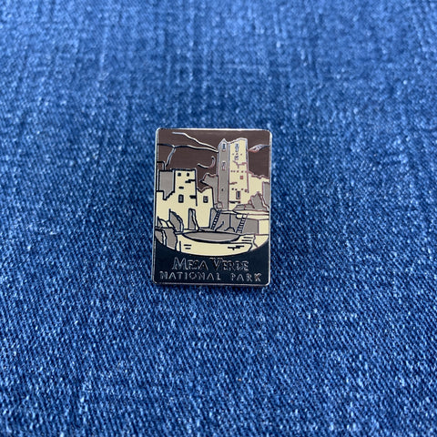 Pin with a design of a mesa verde national park mountain and buildings on a blue denim background