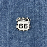 An Arizona Route 66 shield-shaped embroidered patch with black and white embroidery, shown on a blue denim fabric background.