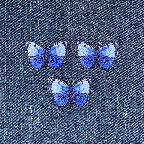 Three blue butterfly patches on a denim background