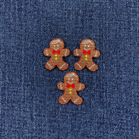 Three embroidered gingerbread man patches on a denim background
