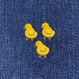Three yellow chick patches on a blue denim background