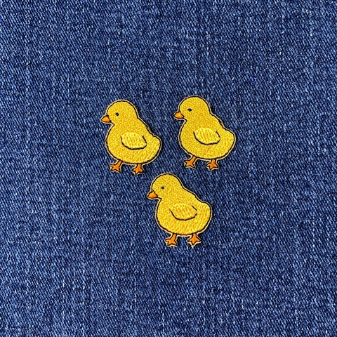 Three yellow chick patches on a blue denim background