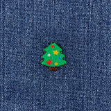 A small embroidered Christmas tree patch with colorful stars and ornaments, placed on a textured blue denim fabric background.