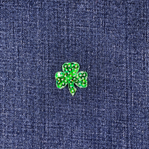 Green sequin shamrock patch on a blue denim background