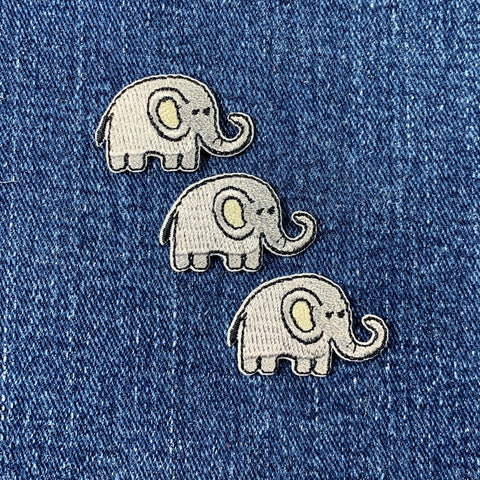 Three embroidered elephant patches on a denim background