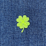 Green four-leaf clover patch on blue denim fabric