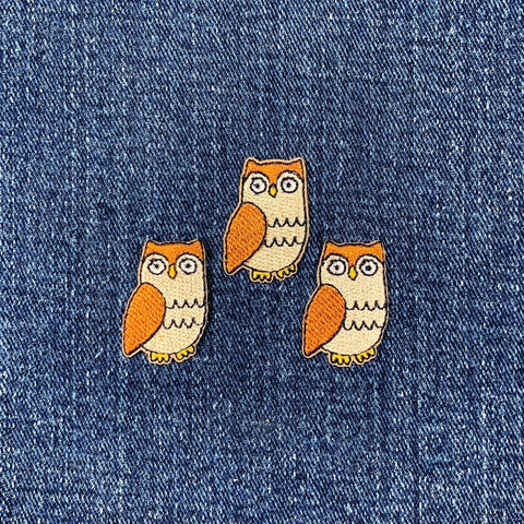 Three owl-shaped patches on a denim background