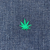 Green cannabis leaf patch on blue denim fabric