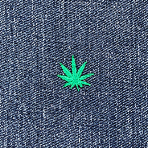 Green cannabis leaf patch on blue denim fabric