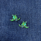 Two green turtle-shaped patches on a blue denim background