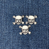 Three skull and crossbones patches on a denim background