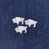 Three white buffalo-shaped patches on a denim background