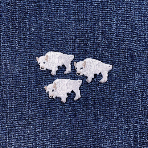 Three white buffalo-shaped patches on a denim background