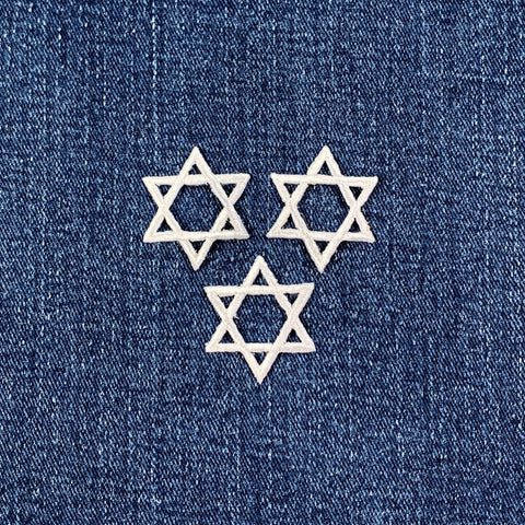 Three white Star of David patches on a denim background