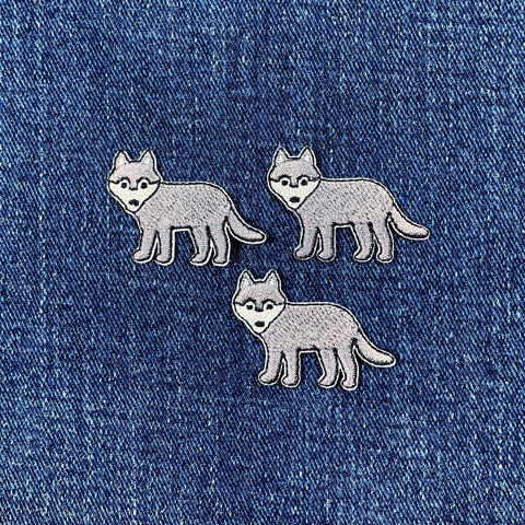 Three wolf-shaped patches on a denim background