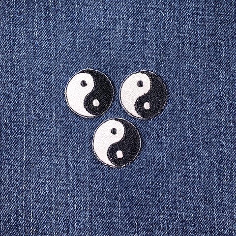Three mini yin yang symbol patches on a denim background