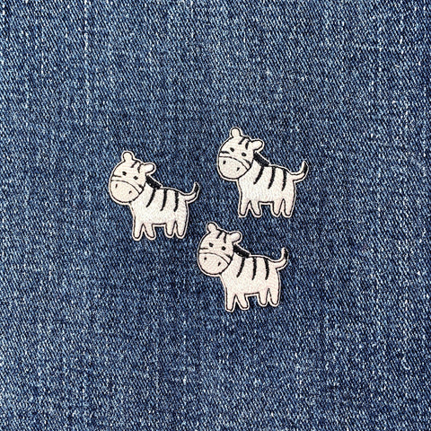 Three zebra-shaped patches on a denim background