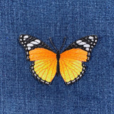 Butterfly patch with orange and black wings on blue denim fabric