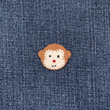 Felt patch with a monkey face design on a denim background