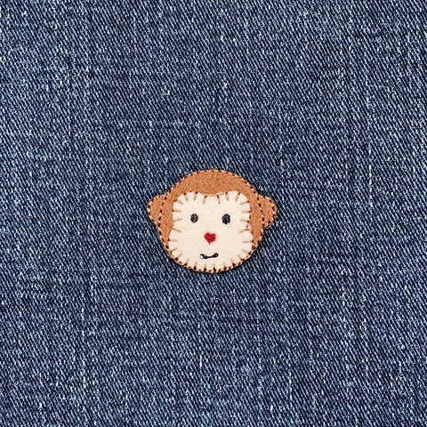 Felt patch with a monkey face design on a denim background