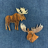 two moose patches displayed on a denim background