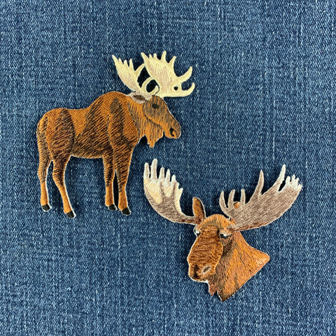 two moose patches displayed on a denim background