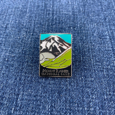 Mountainside pin with 'Mount Rainier National Park' text on a blue denim background