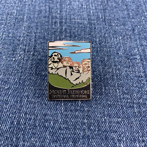 A pin badge featuring an illustration of Mount Rushmore National Memorial with the text 'Mount Rushmore National Memorial' at the bottom on a denim background