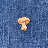 Embroidered patch depicting a brown mushroom with a textured cap and stem on a denim background.