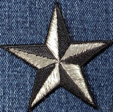 a silver and black 3-D nautical style star patch on a denim background