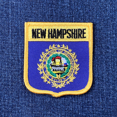 Embroidered patch of New Hampshire's coat of arms on a blue denim background